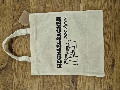 Stofftasche mit schwarzem Druck "HECHSEL-SACHEN" und "ART" in einem modernen Schriftstil.