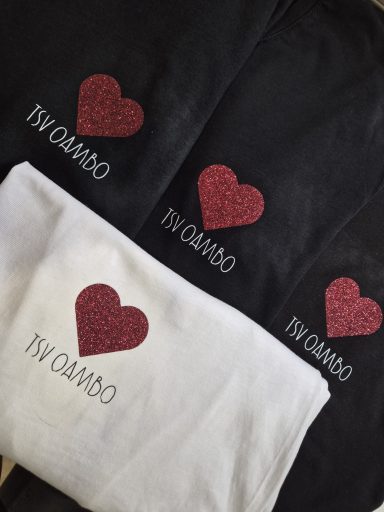 Schwarze und weiße Textilien mit glitzerndem Herzdesign und dem Schriftzug „TIV DAMO".