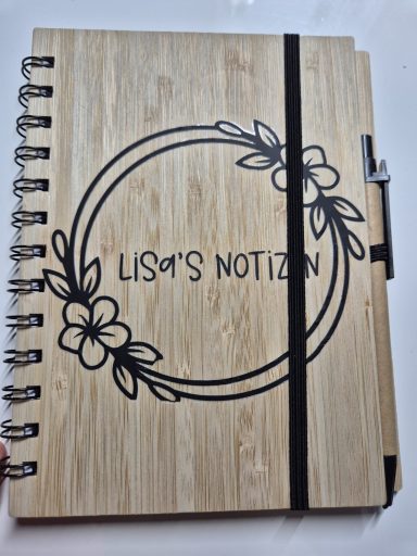 Holzspiralnotizbuch mit floralem Design und dem Schriftzug "Lisa's Notizen".