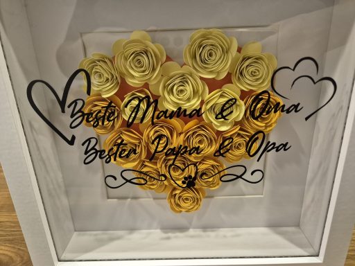 Ein herzförmiger Rahmen mit gelben Rosen und dem Schriftzug "Beste Mama & Anna".