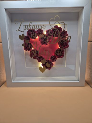 Roter Herzrahmen mit beleuchteten Blumen und goldener Schrift „Liebes-Design“.