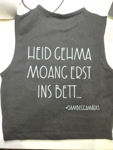 Schwarzes ärmelloses Oberteil mit dem Text: "Heid gehma moang erst ins Bett."